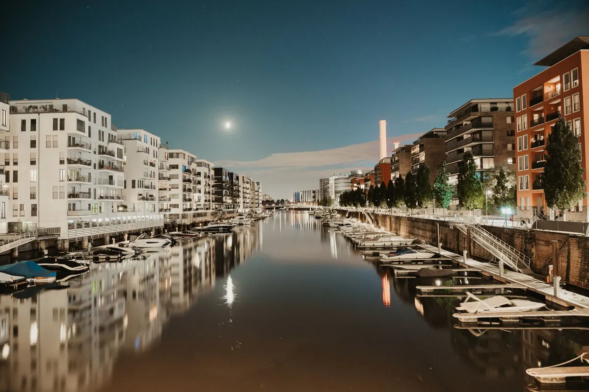 Peaceful night view of the urban waterfront in Frankfurt with moored boats and illuminated buildings, floating dock mandurah