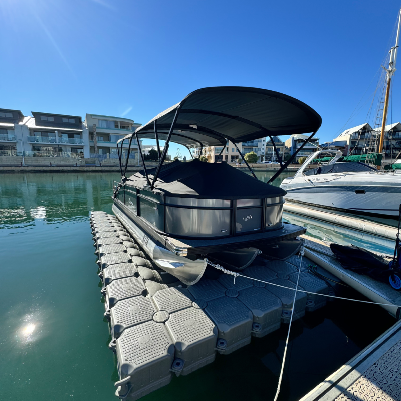 Luxury pontoon boat docked at a modern marina under a clear blue sky